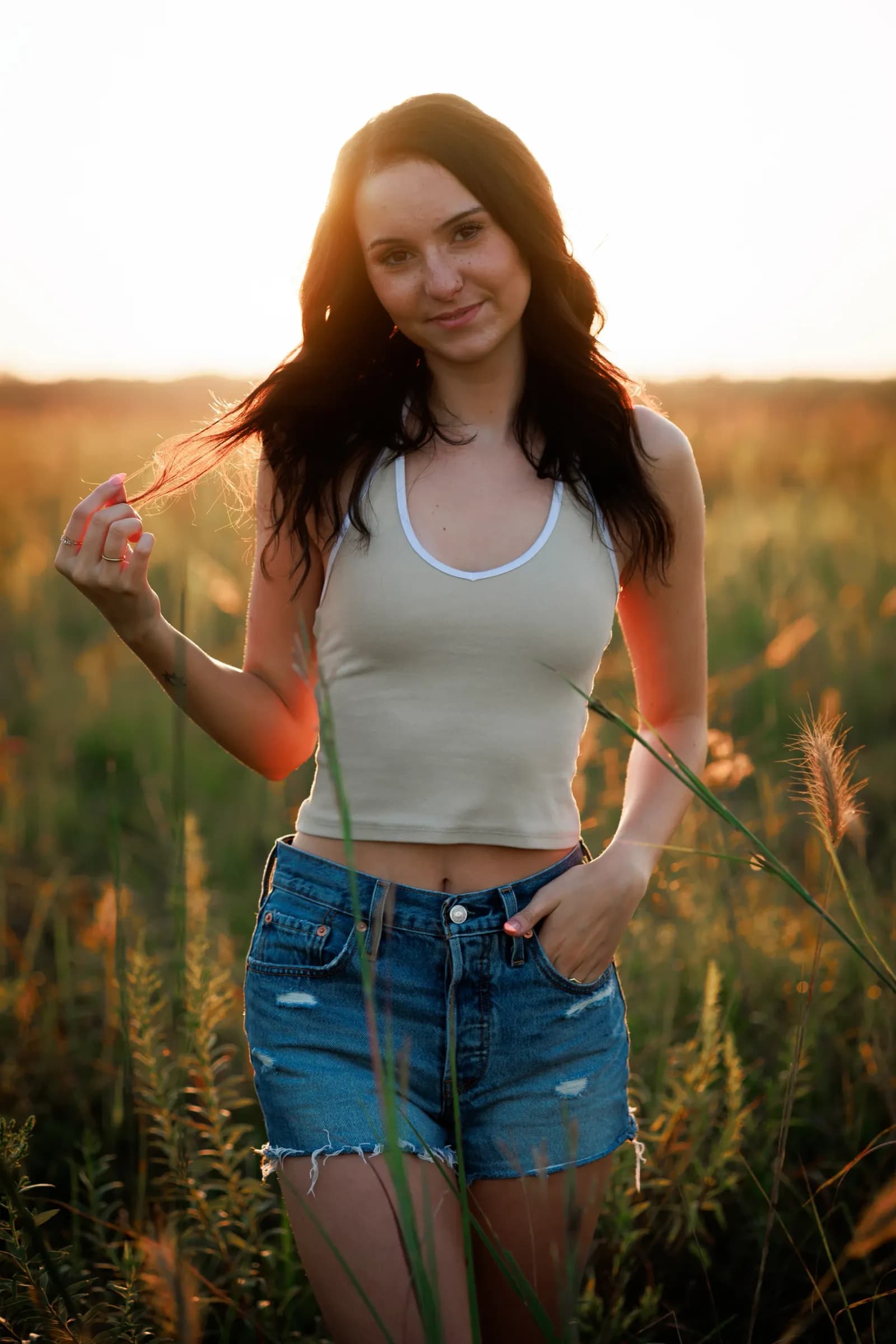 Girl in tall grass with sunset behind during golden hour
