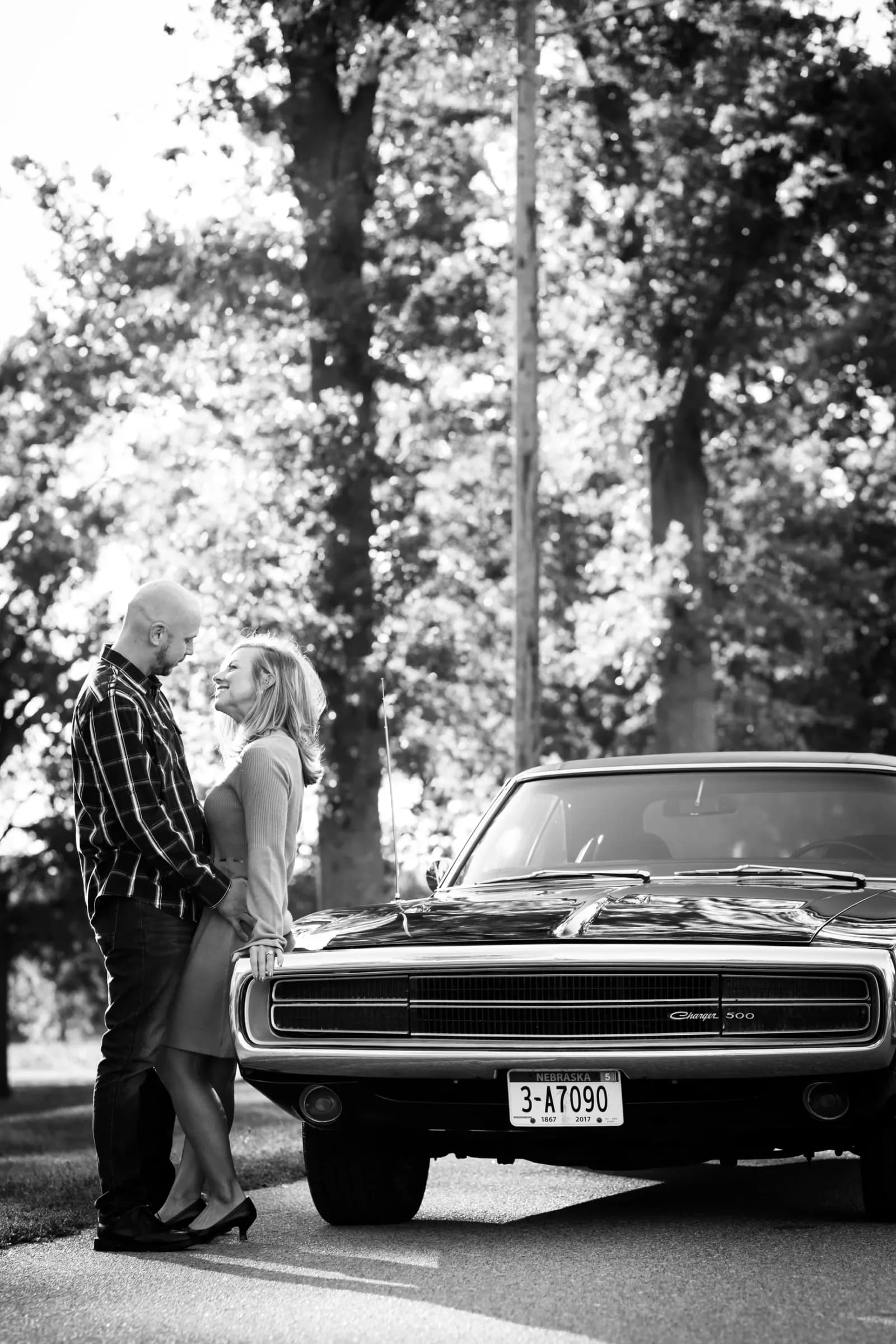 Black and white engagement photo of couple wth classic car