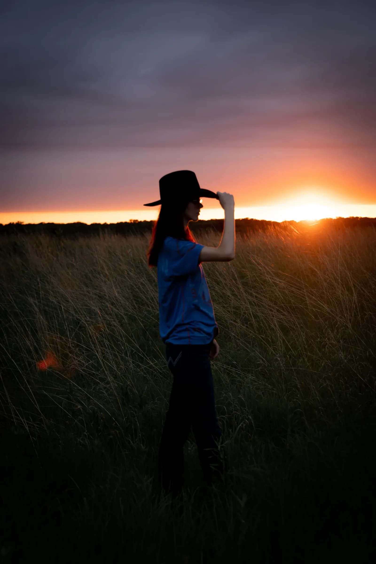 Girl with cowboy hat silhouette against sunset