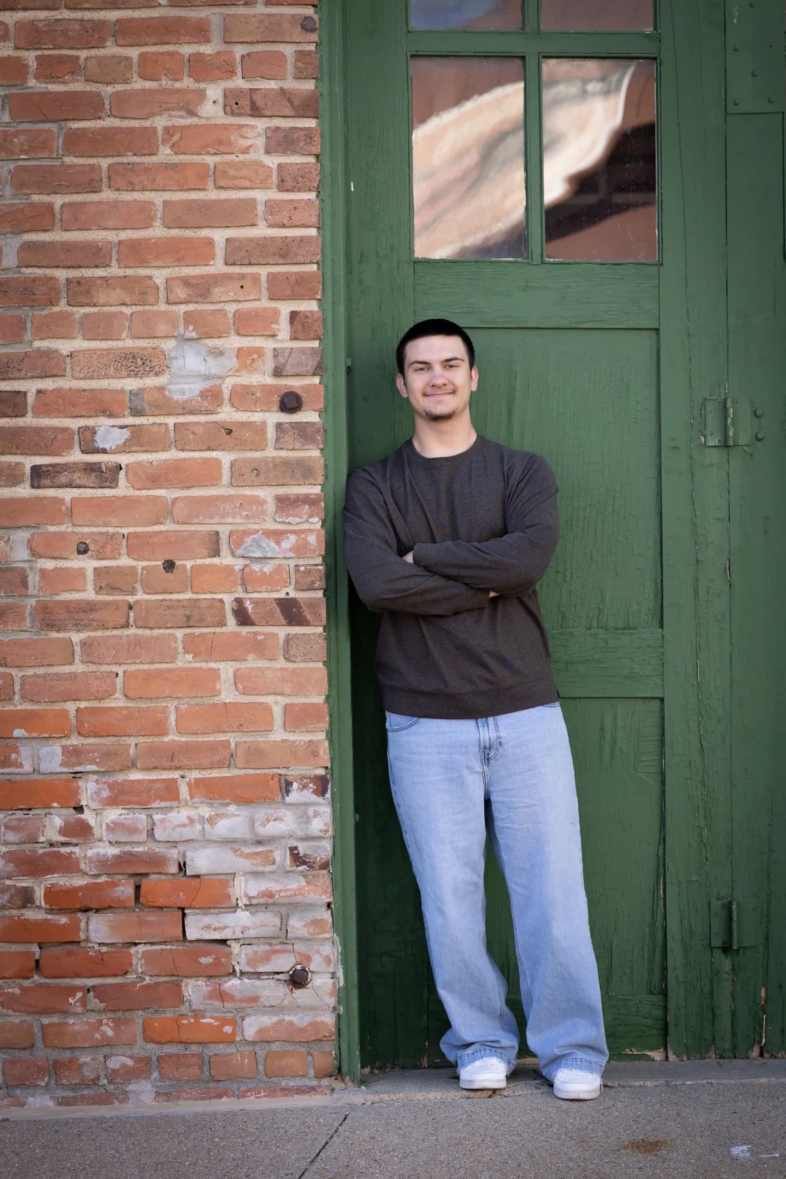 Boy in front of green door and brick background