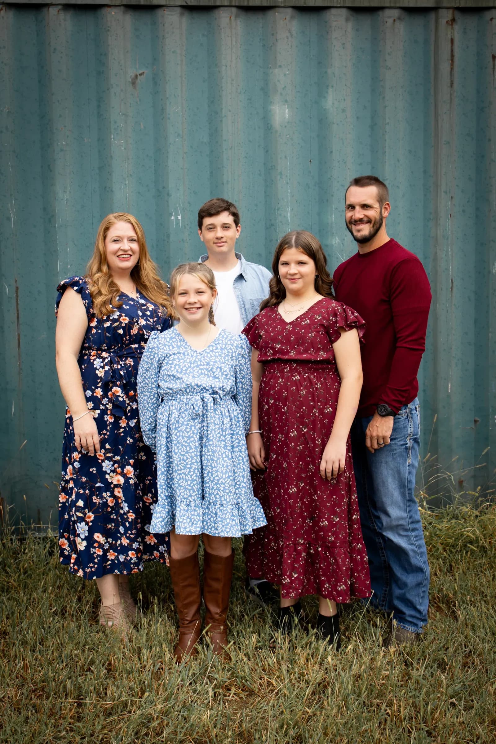 Family of 5 posed on green wall