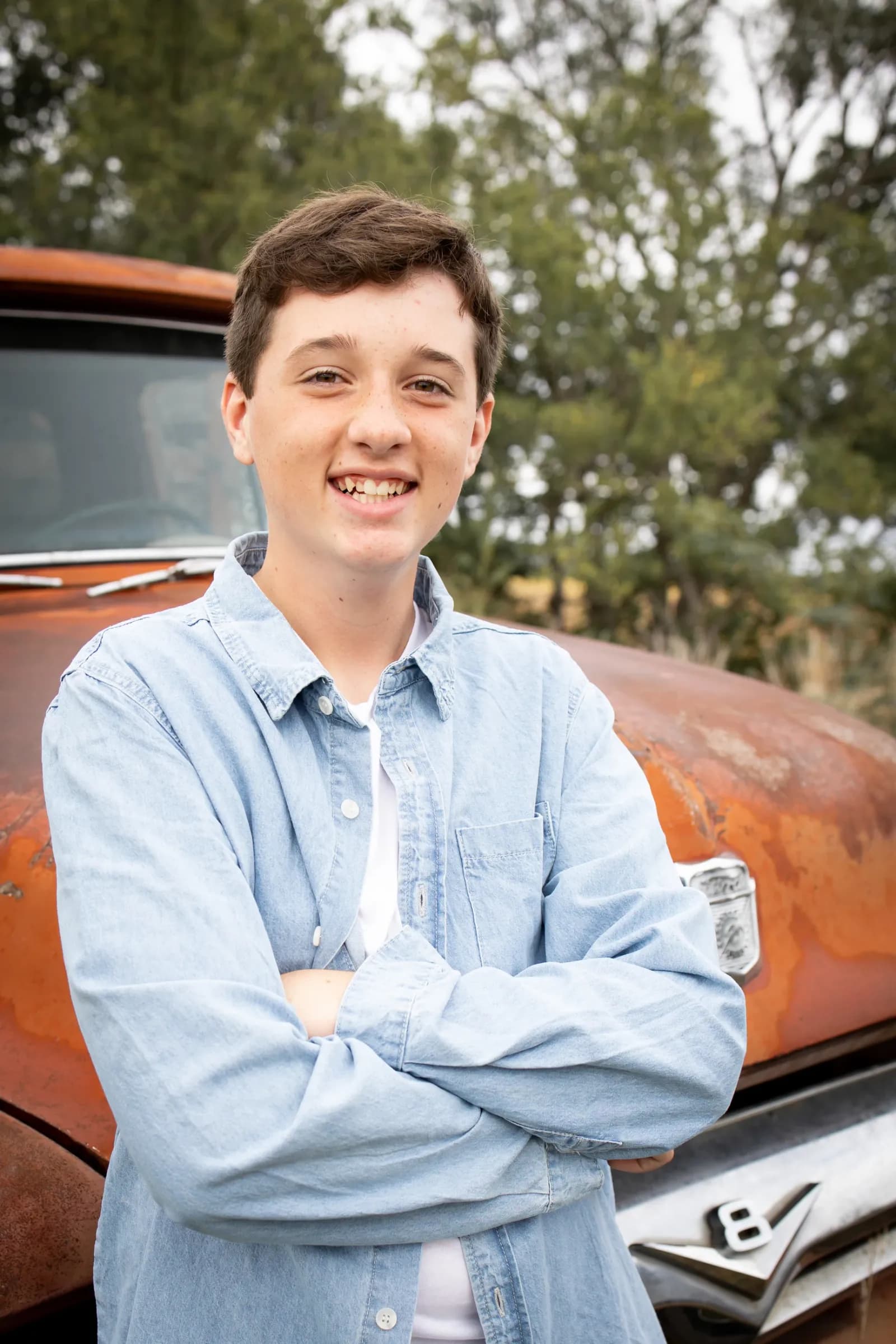 Teen boy posing in front of rusted antique truck